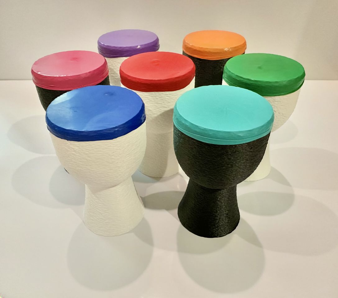 Seven 3D-printed hand drums with brightly colored drumheads.