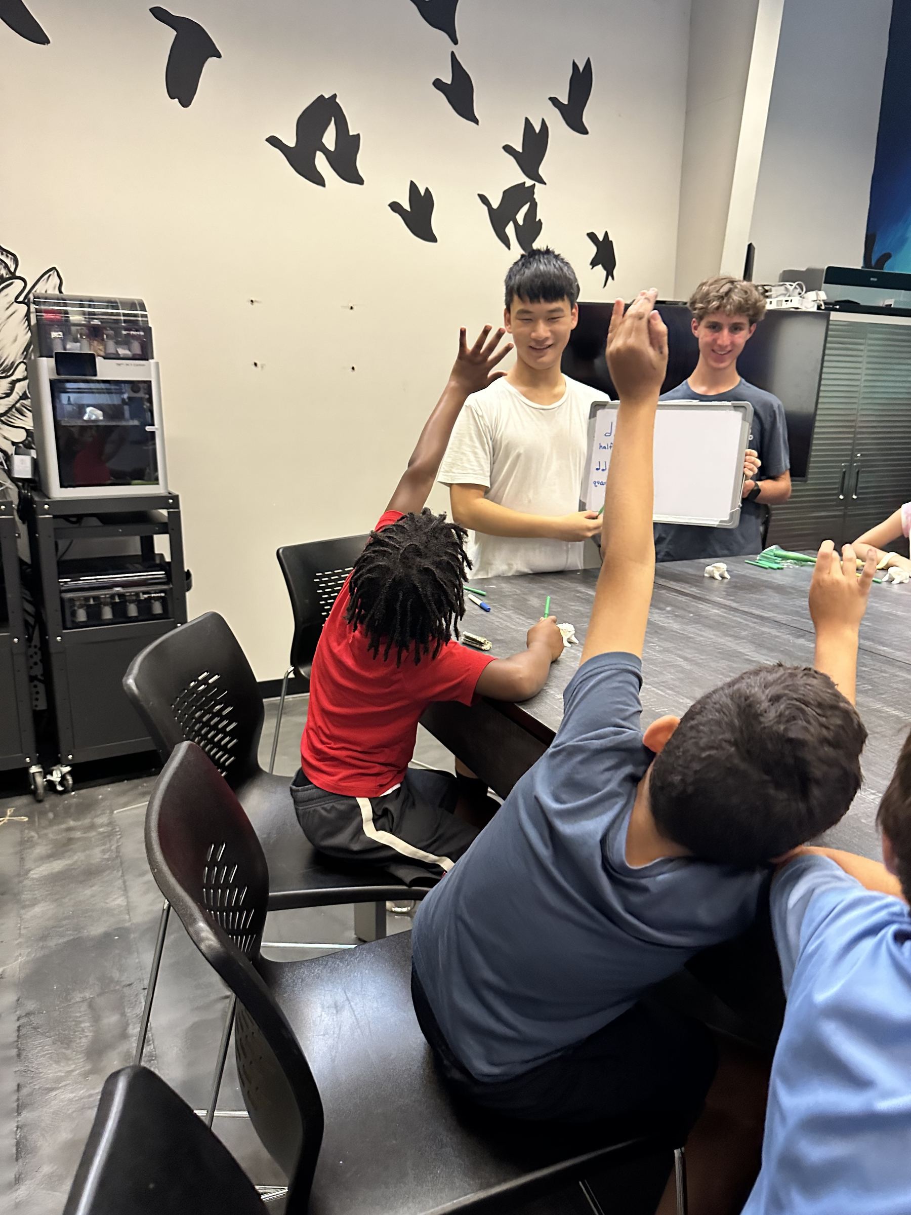 Students raising their hands during a Print2Play workshop activity.